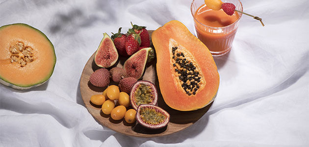 This image shows a bowl of fruits including papaya, figs strawberries and more