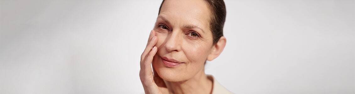 The image shows an older woman looking directly at the audience