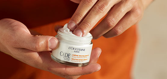 The image shows a man about to apply  the L'OCCITANE Cade Revitalising Cream