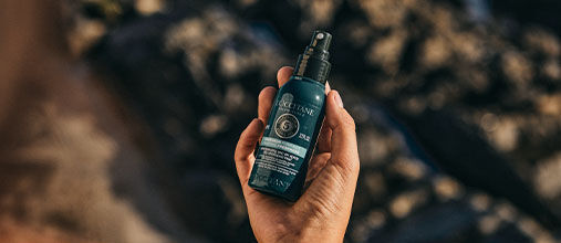 The image shows someone holding the L'OCCITANE Purifying Freshness Dry Shampoo Mist