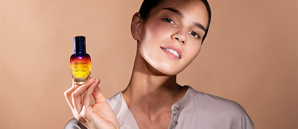A woman holding the L'OCCITANE Immortelle Overnight Reset Eye Serum 