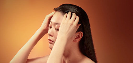 The image shows a woman gently massaging her scalp