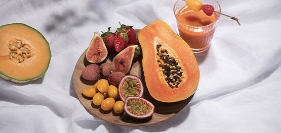 This image shows a bowl of fruits including papaya, figs strawberries and more