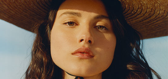 The image shows the face of a woman looking straight to the audience