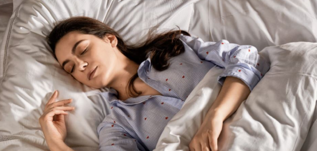 A woman sitting on her bed holding the L'OCCITANE Cocoon &Serenite Candle