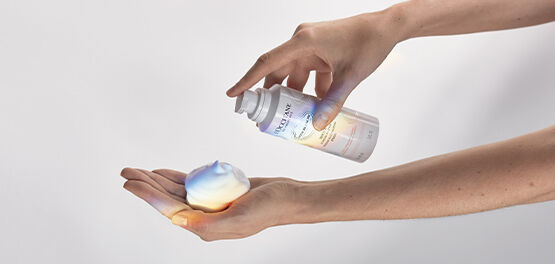 A close-up image showing the hands of a person applying the L'OCCITANE Reine Blanche Intense Illuminating Foam