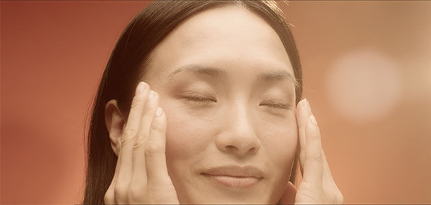The image shows a woman massaging her face