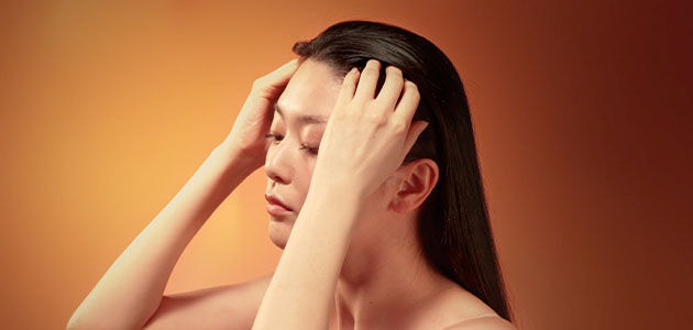 The image shows a woman gently massaging her scalp