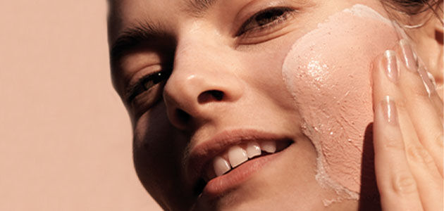 The image shows a woman gently massaging her face
