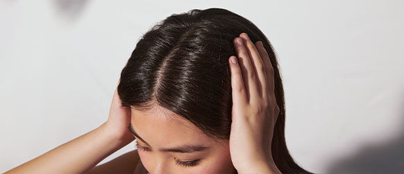 The image shows the head of a woman focusing on the scalp