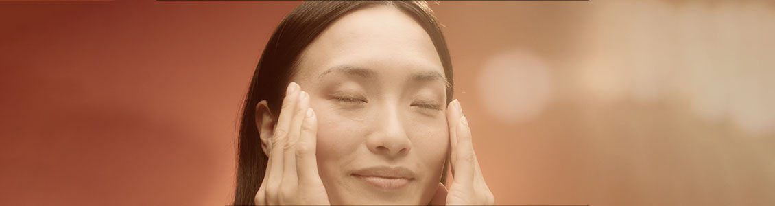 The image shows a woman massaging her face