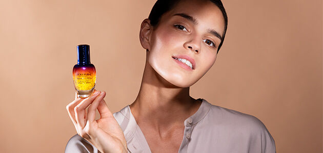 Image shows a woman holding the L'OCCITANE Immortelle reset serum 