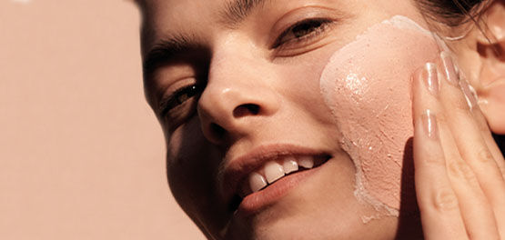 The image shows a woman gently massaging her face