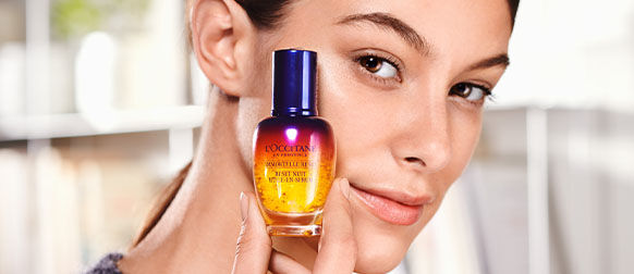 Woman holding Immortelle Overnight Reset Serum.
