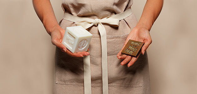 Craftswoman holding L'OCCITANE Bonne M&egrave;re Soap Bar and stamp used in the manufacturing process, Savon de Marseille, Provence